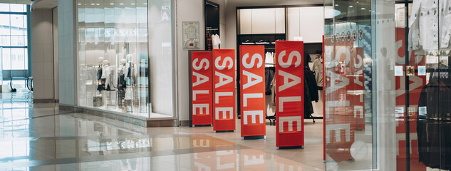 Red banners SALE on anti-thieft gate sensor at clothing store entrance. Black friday sale and seasonal discounts