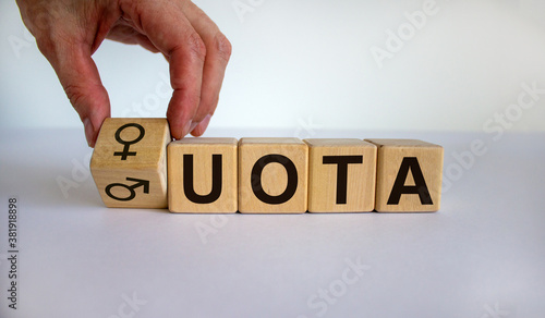 Symbol for womens quota. Hand turns a cube and changes the expression of 'mens quota' to 'womens quota'. Beautiful white background, copy space. Lifestyle concept.