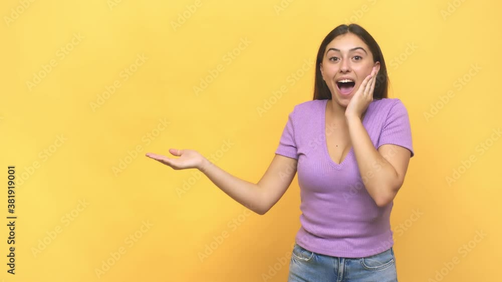 Young caucasian woman holds copy space on a palm, keep hand over cheek amazed and delighted Young caucasian woman holds copy space on a palm, keep hand over cheek amazed and delighted