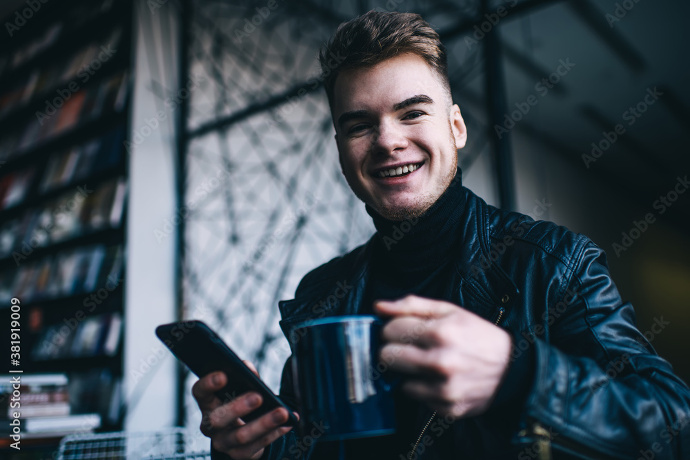 Joyful man enjoying coffee and browsing smartphone Joyful man enjoying coffee and browsing smartphone