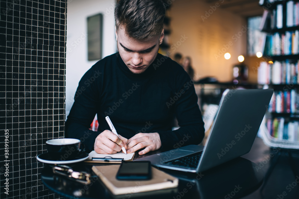 Focused man taking notes while working Focused man taking notes while working