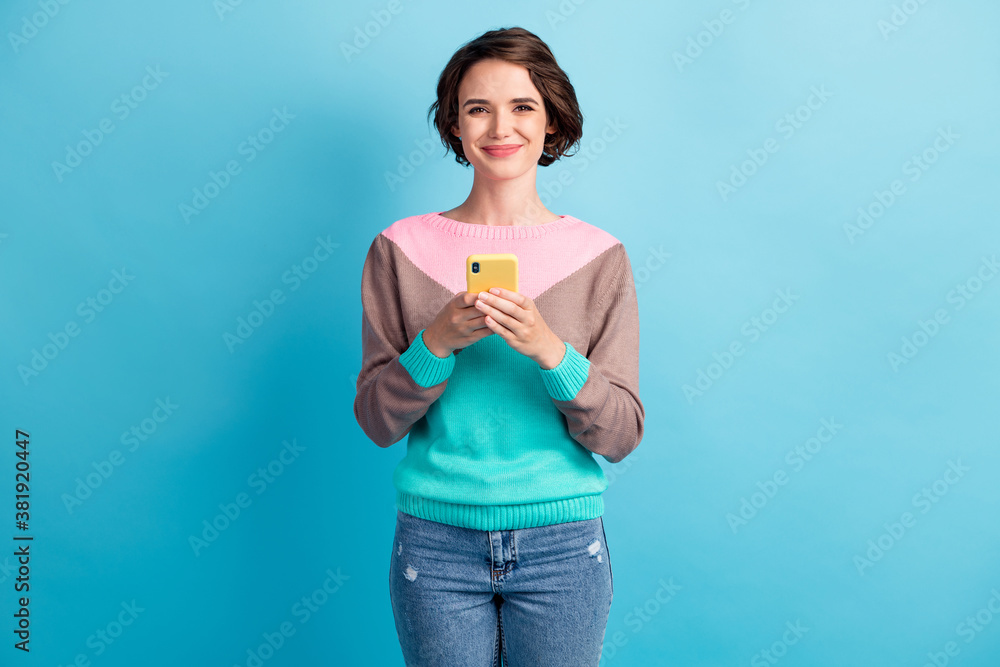 Photo portrait of woman holding phone in two hands isolated on pastel light blue colored background Photo portrait of woman holding phone in two hands isolated on pastel light blue colored background