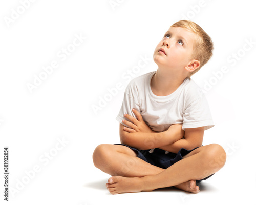 Litlle boy sitting on the floor and looking up on white background