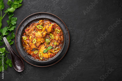 A Chicken Patiala in black bowl on dark slate table top. Murg Patiala is indian cuisine curry dish with chicken meat, spices, curd and cashew nut paste. Asian food and meal. Copy space
