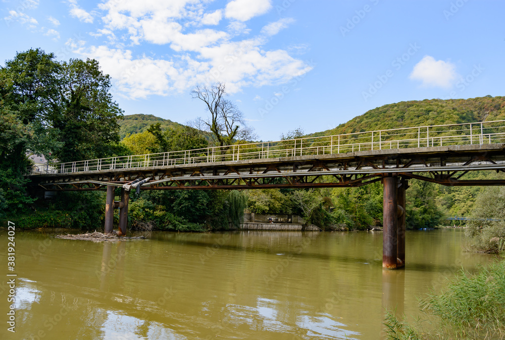 Beautiful mountain range with a bridge over the river in summer against a blue sky with clouds. blurry focus Beautiful mountain range with a bridge over the river in summer against a blue sky with clouds. blurry focus