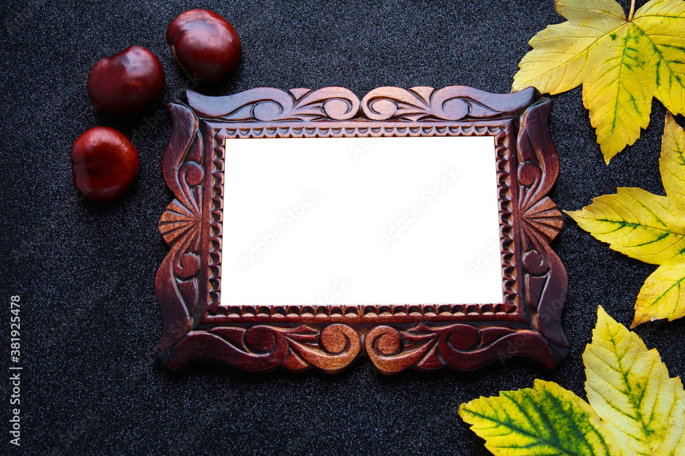 Wooden carved frame on a black background with autumn foliage.
