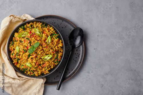 Masala Egg Bhurji or Muttai Podimas in black bowl on gray concrete table top. Anda Bhurji is indian cuisine scrambled eggs dish with spices. Asian food and meal. photo