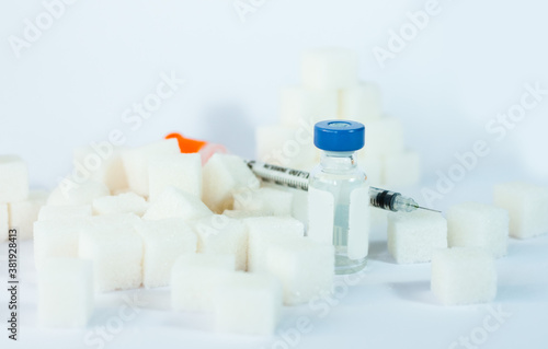 Sugar addiction  insulin resistance  unhealthy diet  sugar cubes pyramid  bottles of insulin and syringe for vaccinationon white background  diabetes protection medical concept  top view.