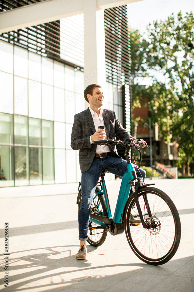 Young businessman on the ebike with takeaway coffee cup Young businessman on the ebike with takeaway coffee cup