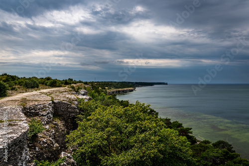 Landscape coastline view of limestone cliffs at the island Gotland in Sweden with thunder clouds and horizon in the background.