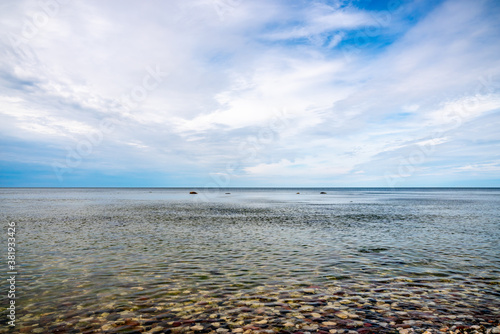 Fototapeta Naklejka Na Ścianę i Meble -  Calm beautiful ocean summer view of water horizon and sky with pebble stone beach on the island Gotland in the Baltic Sea.