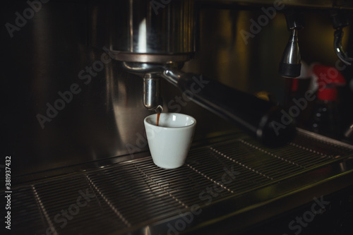 Espresso pouring from coffee machine into coffee cup