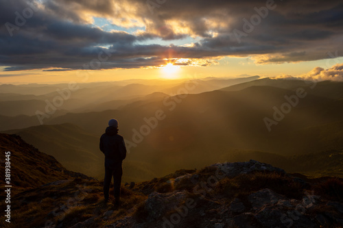 silhouette of the man at the top of the mountains peak looking at sunset © phpetrunina14