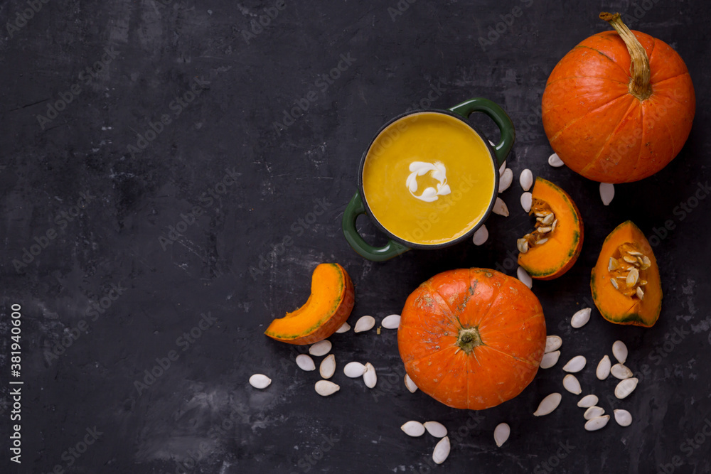pumpkin soup on a dark table. pumpkin slices, seeds and a whole pumpkin. Healthy eating. Copy space