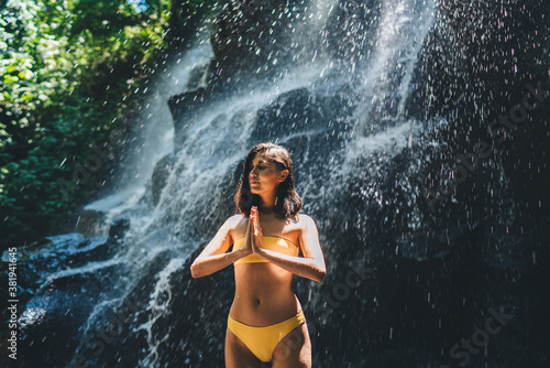 Calm woman meditating near waterfall