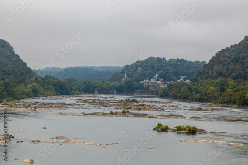 View of Potomac river as seen from the Sandy Hook Bridge in Washington County  MD. A large body of water with forest covered hills on river banks. At distance Harpers Ferry  a scenic town is seen.