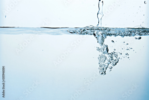 Close up of clean blue water and splash with bubbles of air isolated on white background. Diet, health and nature concept. Copy space..