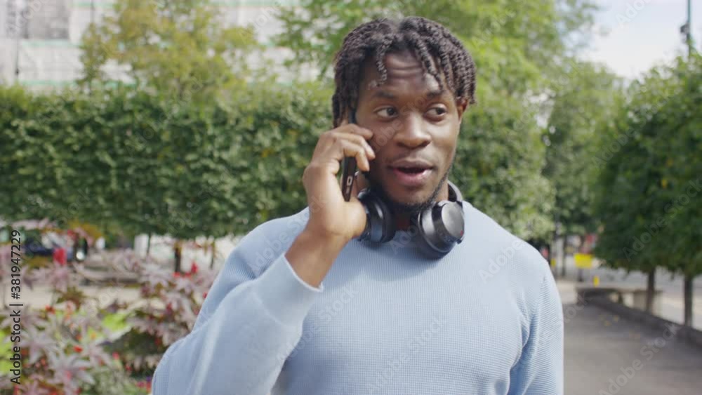 Handsome black male walks through town talking on his phone, in slow motion Handsome black male walks through town talking on his phone, in slow motion