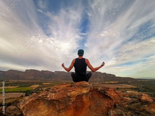 Rear View of Man Meditating on Mountain top Summit Expressing mindfulness & Freedom for Life. Clouds, Epic Sky and Mountain Ranges with Scenic View from the Top, Rocklands, Cederberg, South Africa photo