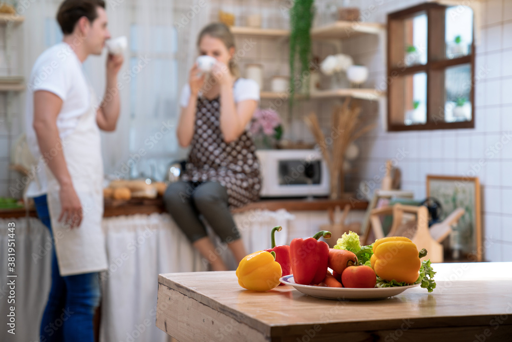 Couple sitting in the kitchen drinking coffee in the morning, Focus on fresh vegetables. Couple sitting in the kitchen drinking coffee in the morning, Focus on fresh vegetables.