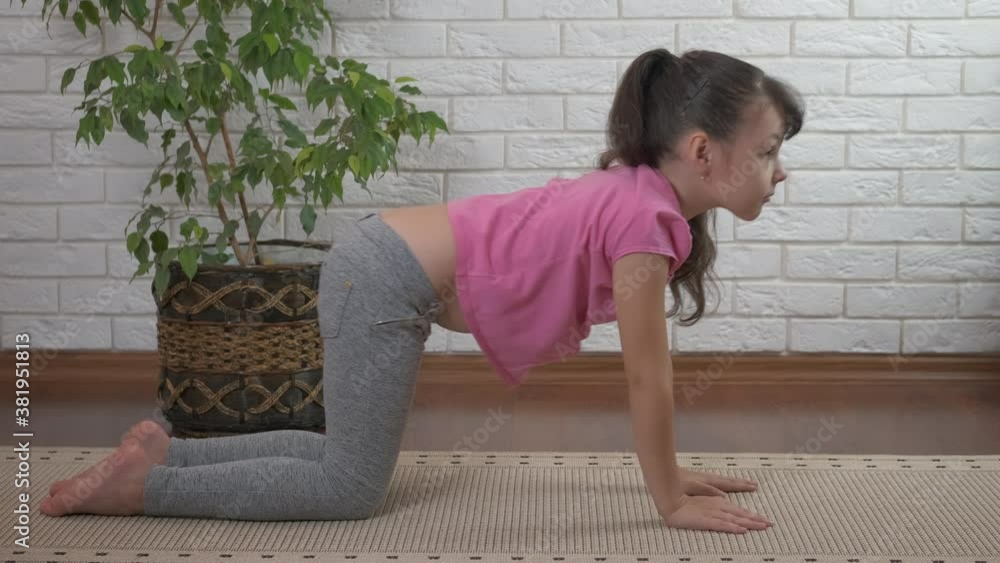 Relax exercise on the floor. A little girl stretches her back and practice yoga asana at home.