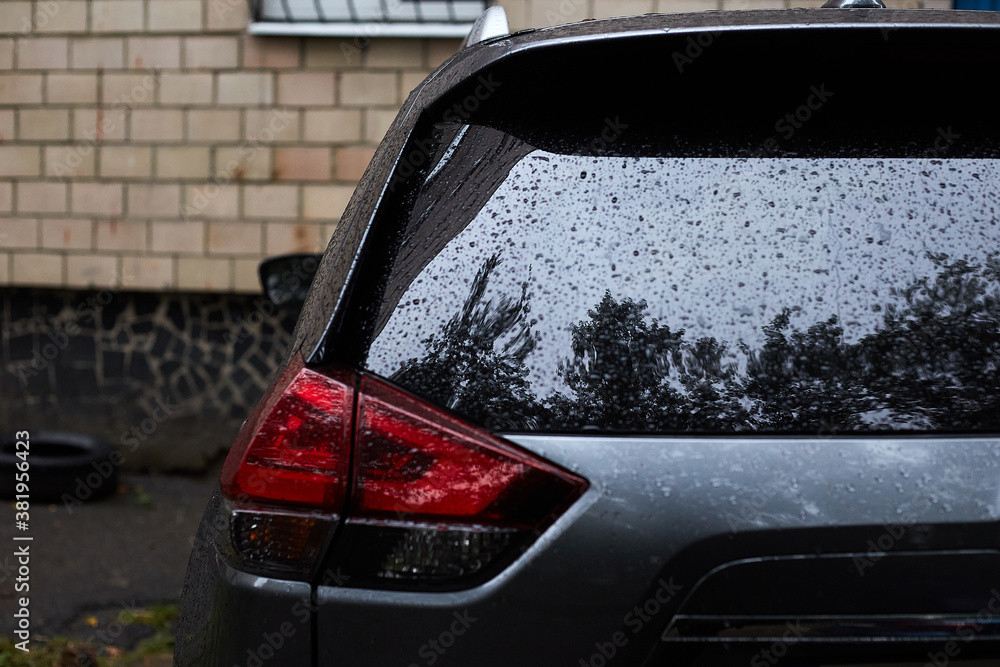 Back window of dark car parked on the street in autumn rainy day, rear view. Mock-up for sticker or decals