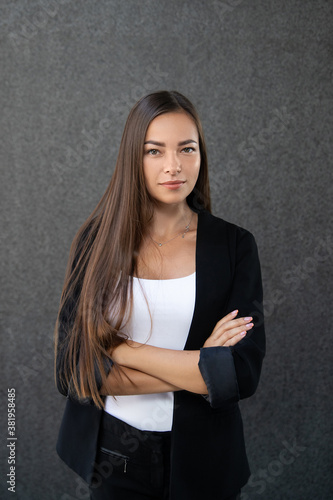 Portrait of young business woman on the grey background. Crossed arms © Larysa
