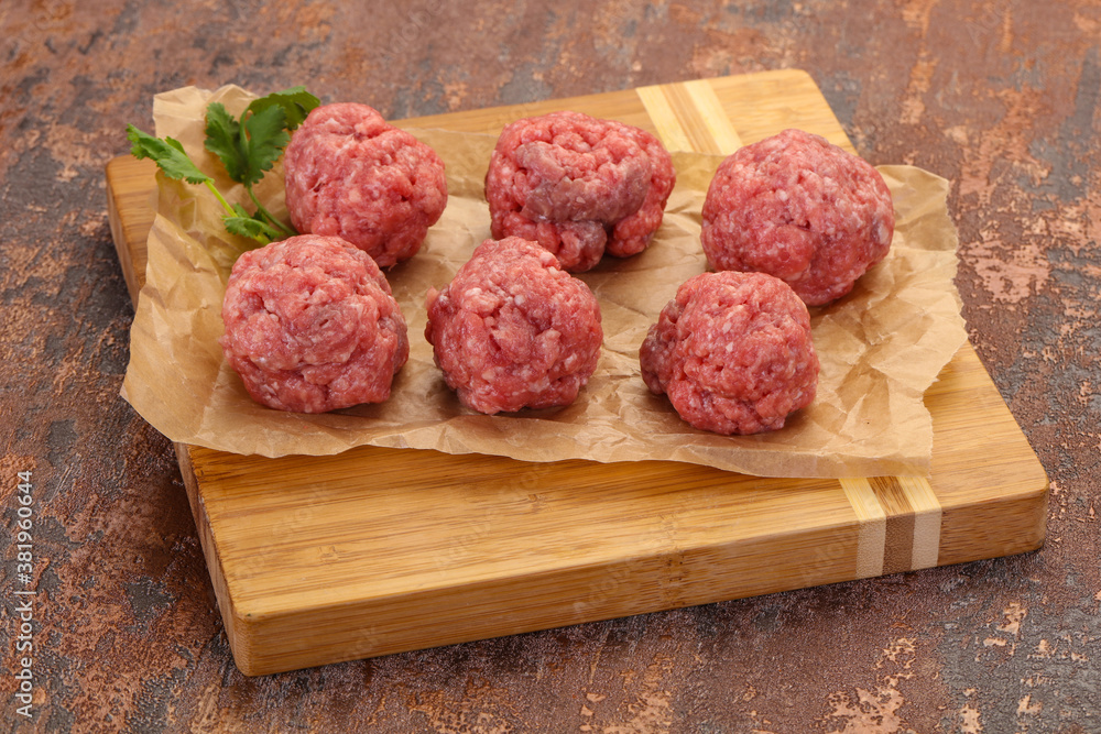 Raw meatball over wooden background Raw meatball over wooden background