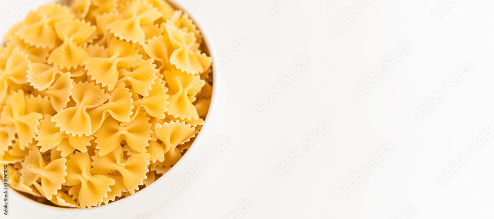 Raw dry uncooked Farfalle pasta spaghetti noodle on white bowl wooden background for basil tomato pesto sauce Homemade Italian food organic whole wheat vegan spaghetti for a healthy meal Raw dry uncooked Farfalle pasta spaghetti noodle on white bowl wooden background for basil tomato pesto sauce Homemade Italian food organic whole wheat vegan spaghetti for a healthy meal