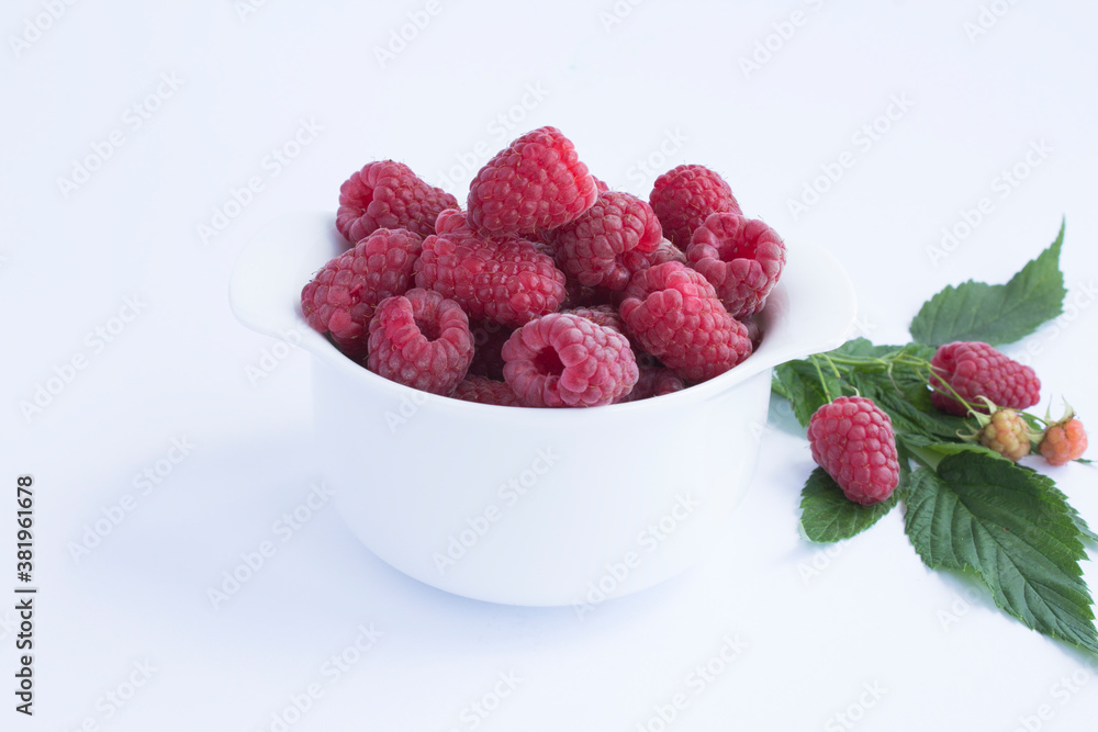 Raspberry and red currant in the white bowl on the white background closeup Raspberry and red currant in the white bowl on the white background closeup