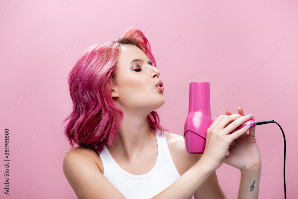 young woman with colorful hair blowing at hairdryer isolated on pink young woman with colorful hair blowing at hairdryer isolated on pink
