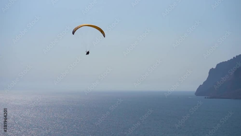 Paragliding in the sky over the sea and mountains Paragliding in the sky over the sea and mountains