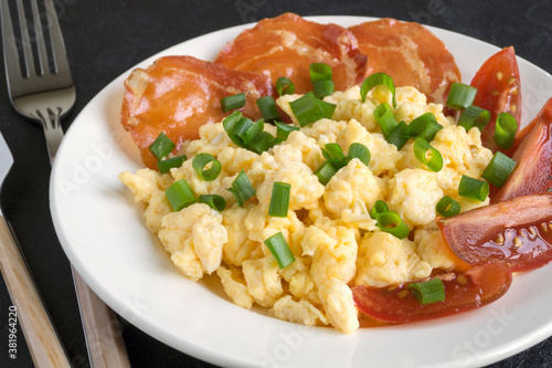 scrambled eggs with tomatoes on a white plate.