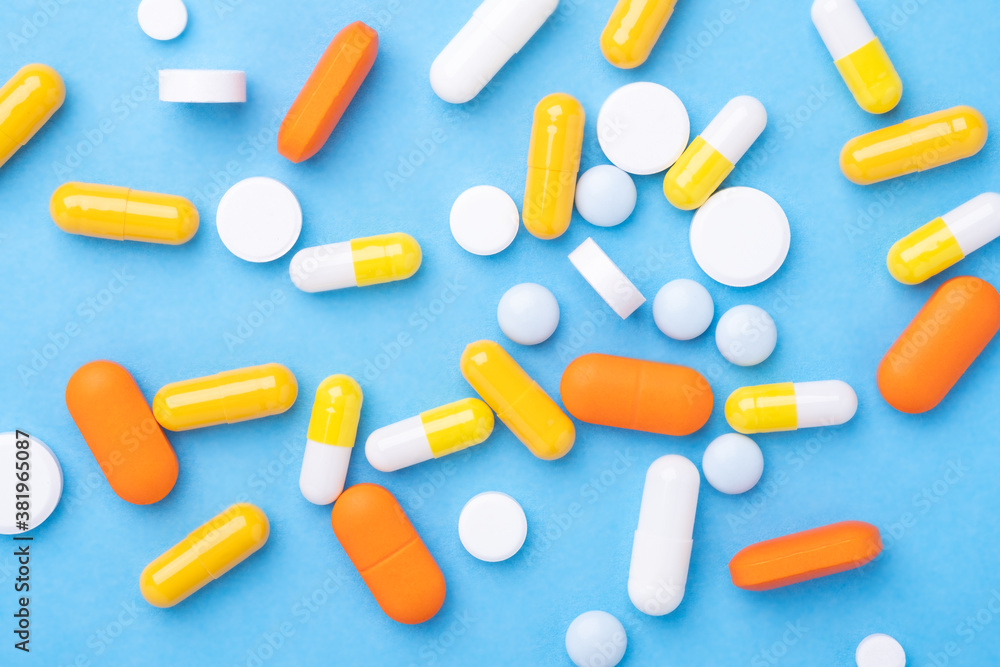 Multicolor tablets and pills capsules on blue background Close-up Top view Multicolor tablets and pills capsules on blue background Close-up Top view