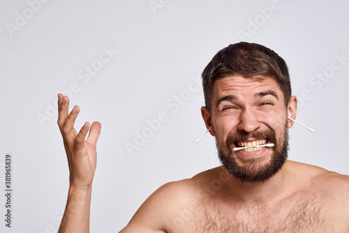 Bearded man with bare shoulders cotton swabs hygiene body care