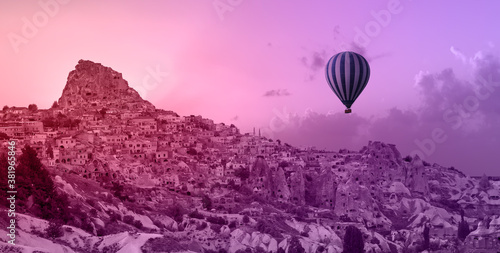 Hot air balloon flying over spectacular Cappadocia at lilac sunset
