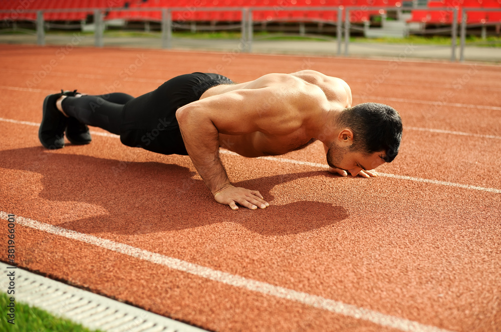 Young athletic man doing push-up exercise in the stadium. Training with your own body weight. Healthy lifestyle. Outdoor sports activities. Young athletic man doing push-up exercise in the stadium. Training with your own body weight. Healthy lifestyle. Outdoor sports activities.