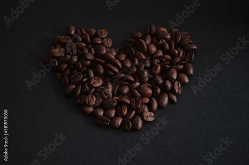 fresh roasted coffee beans on the black background in heart shape