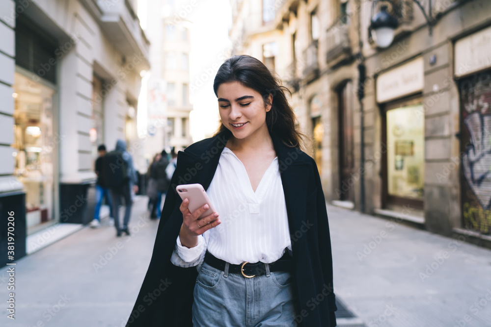 Fototapeta premium Contemplative female tourist thoughtful looking away while waiting for tracking info on smartphone gadget, pensive hipster girl pondering on browser phoning standing at urbanity and thinking