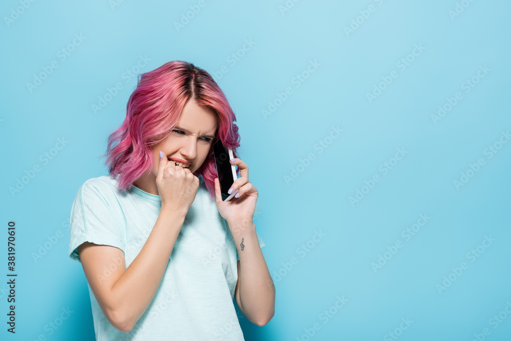scared young woman with pink hair talking on smartphone on blue background scared young woman with pink hair talking on smartphone on blue background