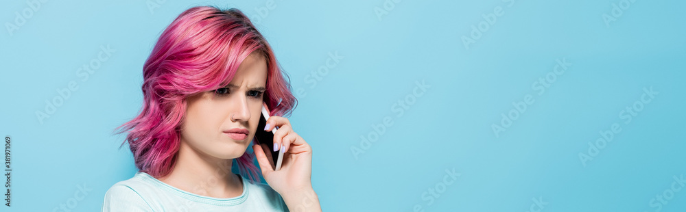 confused young woman with pink hair talking on smartphone on blue background, panoramic shot confused young woman with pink hair talking on smartphone on blue background, panoramic shot
