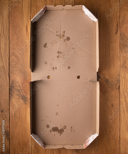 Opened dirty pizza box on wooden background