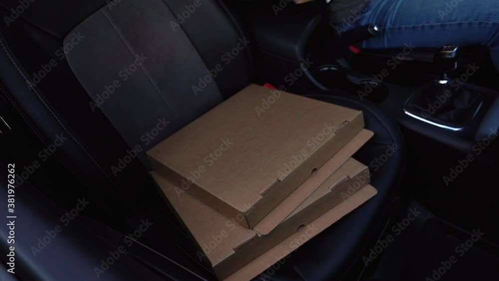 Close-up view of delivery man taking cardboard box with pizza and leaves the car. Handsome courier provides fast delivery of hot food to client. Shooting in slow motion from interior of vehicle. Close-up view of delivery man taking cardboard box with pizza and leaves the car. Handsome courier provides fast delivery of hot food to client. Shooting in slow motion from interior of vehicle.