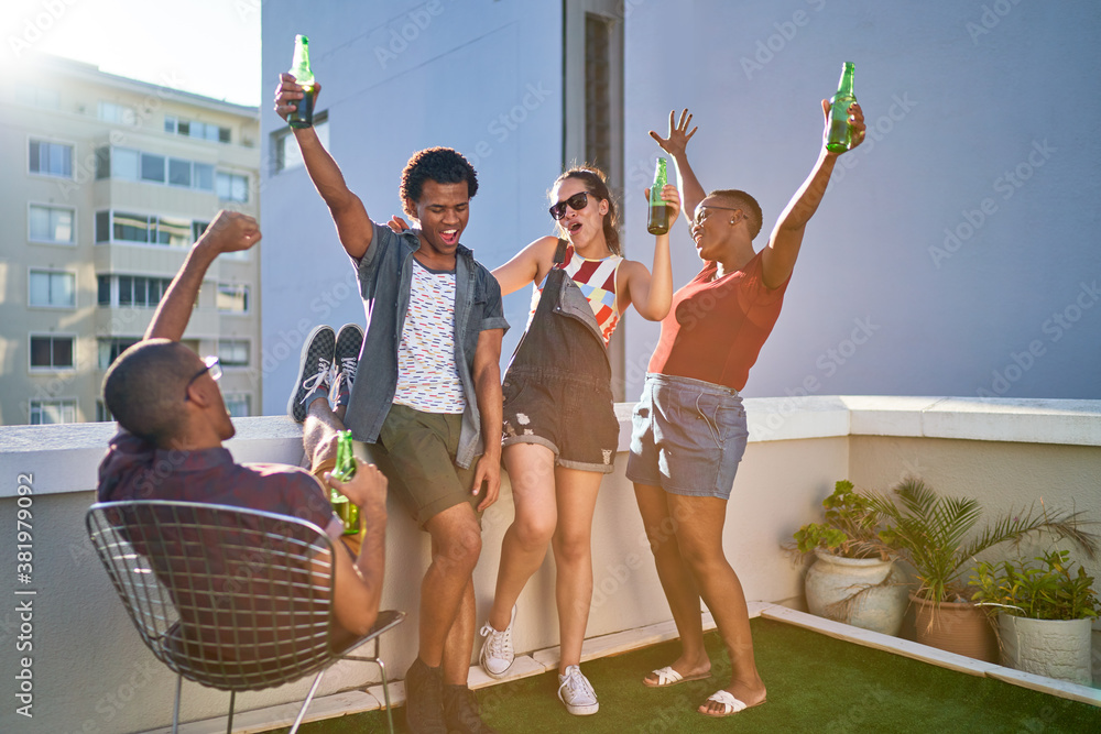 © Trevor Adeline/Caia Image - Happy young friends cheering and drinking beer on urban rooftop © Trevor Adeline/Caia Image - Happy young friends cheering and drinking beer on urban rooftop