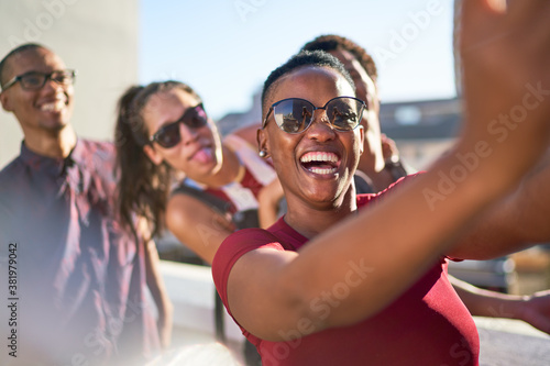 Happy playful young friends taking selfie on sunny patio