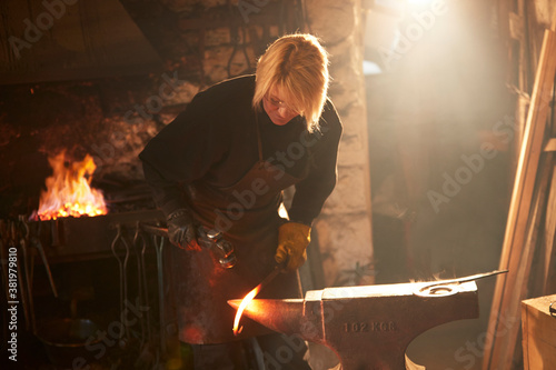 Female blacksmith forging steel in workshop