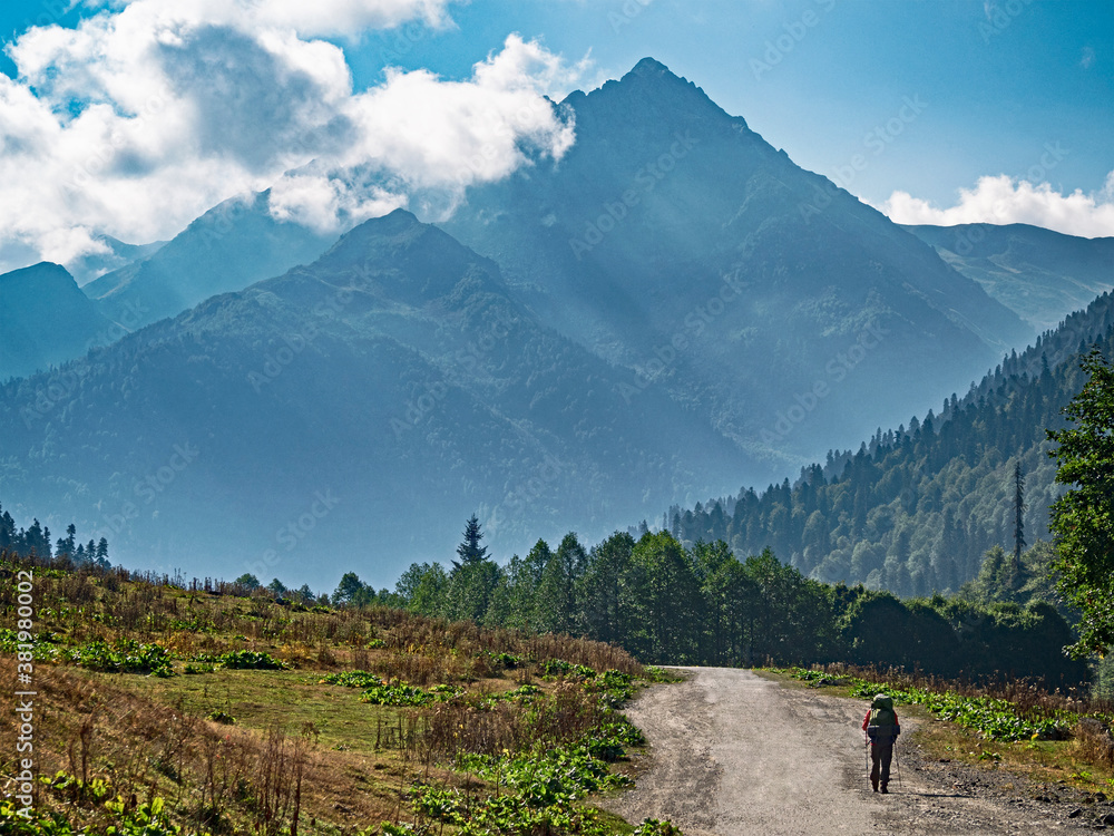 Tourist with backpack on road at mountain range background