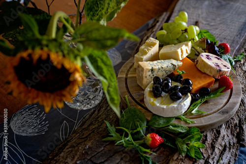 Display of cheeses and olives on a rustic wooden board