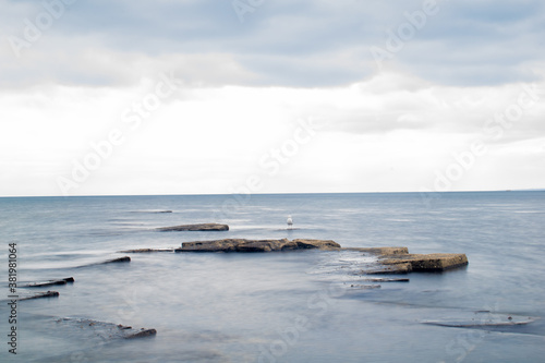 Long exposure shot of rocks sticking out of water and adramatic sky, calm waves and sharp rock formations, beautiful ocean and sky view in Kimmeridge Bay UK photo