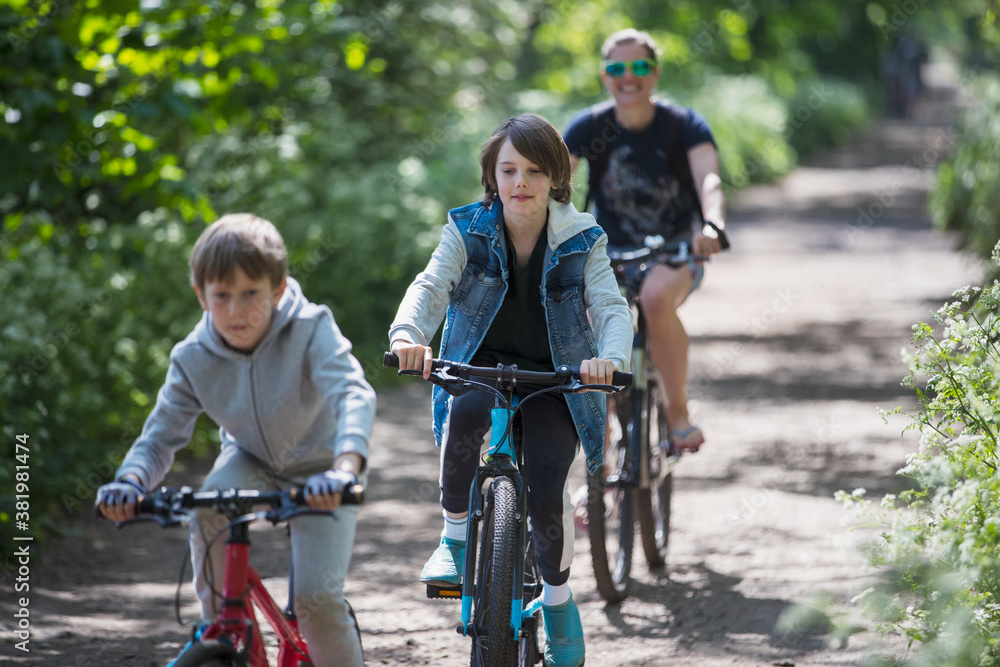 Mother and sons enjoying bike ride on sunny path